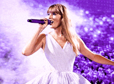 a woman in a white dress is singing into a microphone