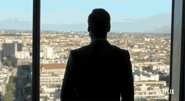 a man in a suit is looking out of a window with netflix written on the bottom