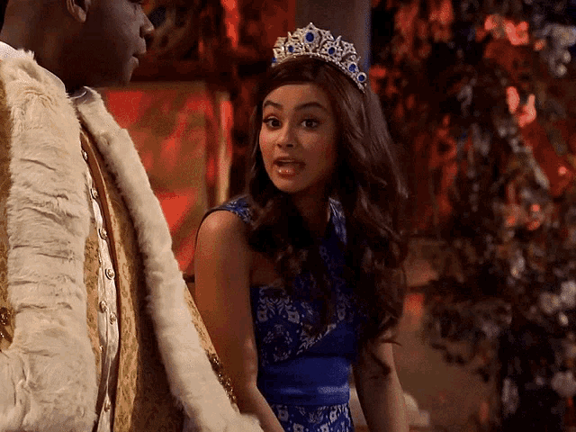 a woman wearing a blue dress and a tiara stands next to a man in a fur coat