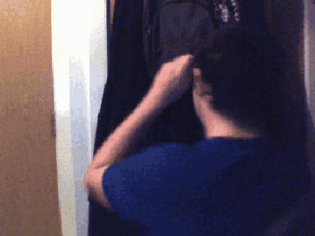 a man in a blue shirt is putting on a black shirt