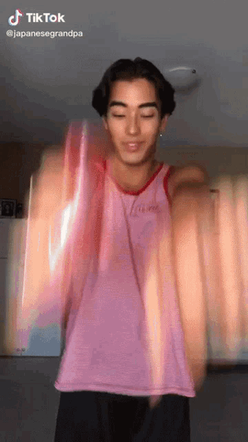 a young man in a pink tank top is dancing on tik tok