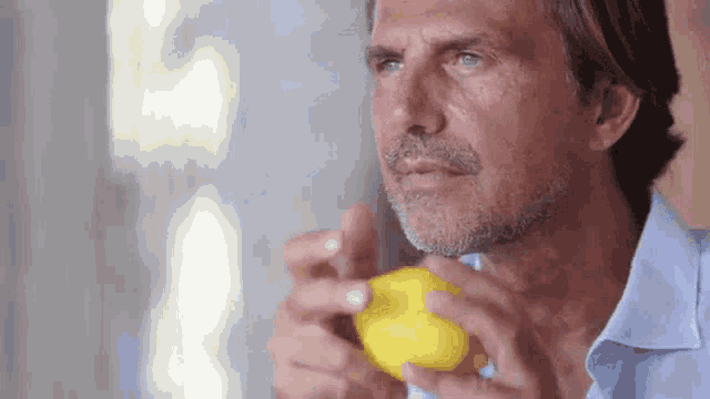 a man in a blue shirt is holding a lemon in his hands