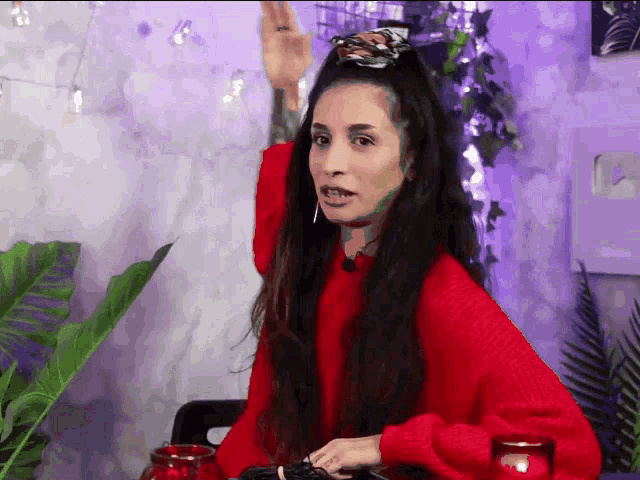 a woman wearing a red sweater is sitting at a table