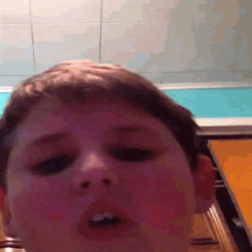 a close up of a young boy 's face with his mouth open .
