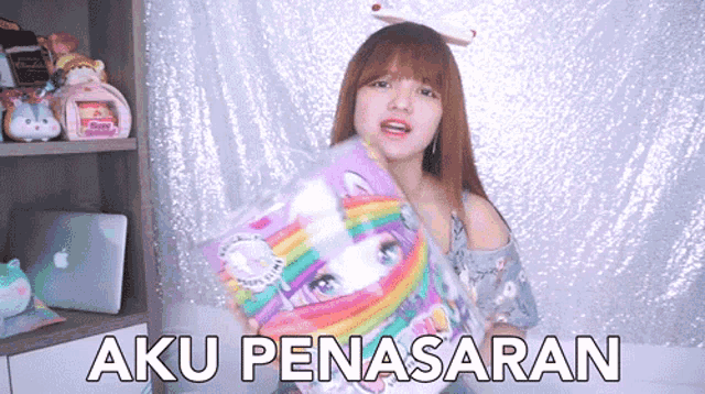 a woman is holding a bag of unicorn slime and says aku penassaran .