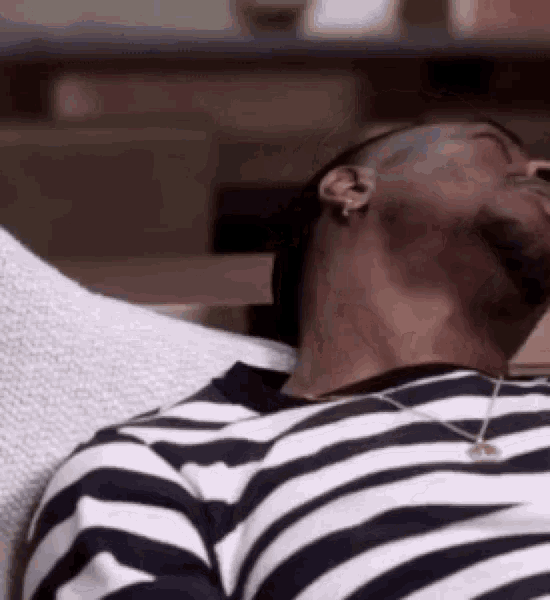 a man in a striped shirt is laying on a couch .