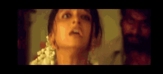 a close up of a woman 's face with a man behind her .