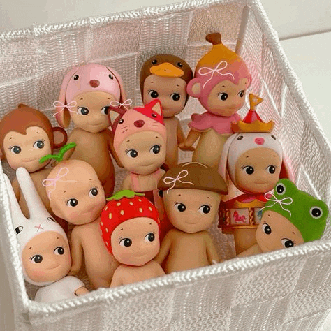 a basket filled with a variety of dolls including a frog and a monkey