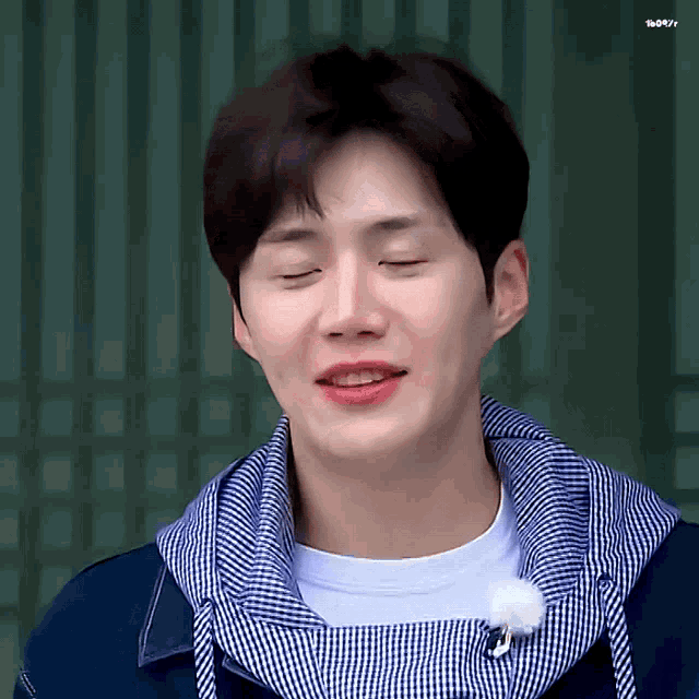 a man with his eyes closed wearing a blue and white plaid shirt