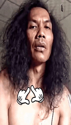 a shirtless man with long hair has a pair of mickey mouse gloves on his chest