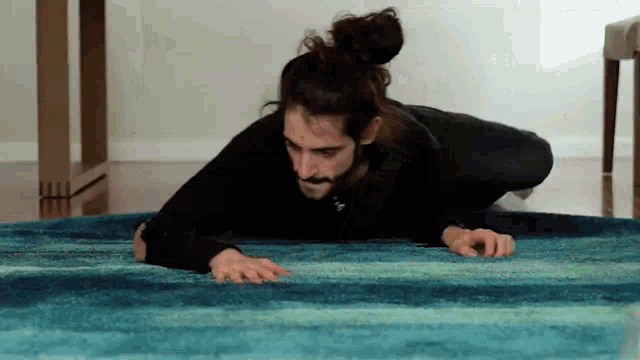 a man is crawling on a blue rug with his hands