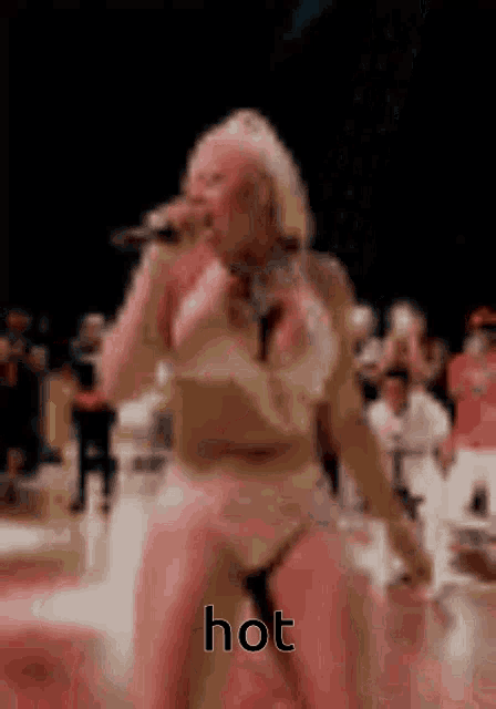 a blurred image of a woman singing into a microphone with the word hot written on the bottom