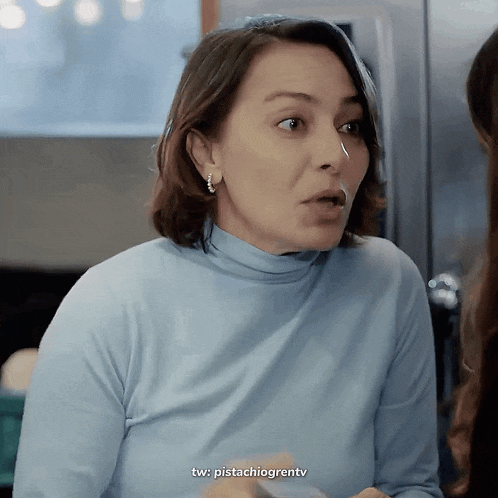 a woman in a blue turtleneck sweater is making a face