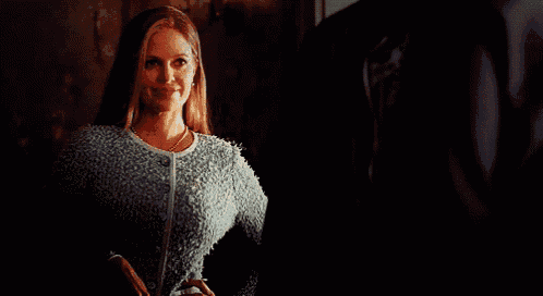 a woman in a blue sweater and pearl necklace
