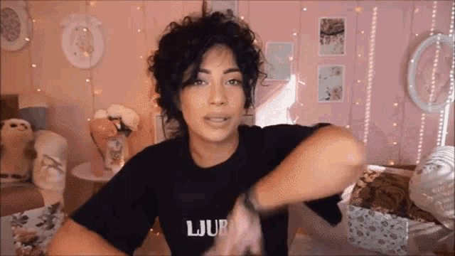 a woman with curly hair wearing a black shirt that says ljup