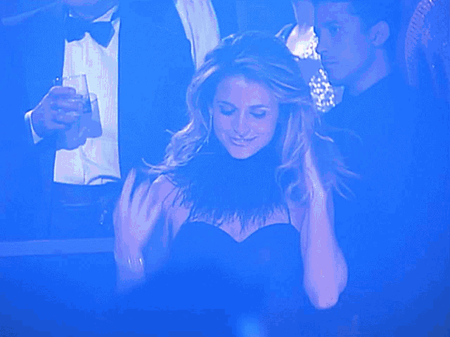 a woman in a black dress stands in front of a blue background