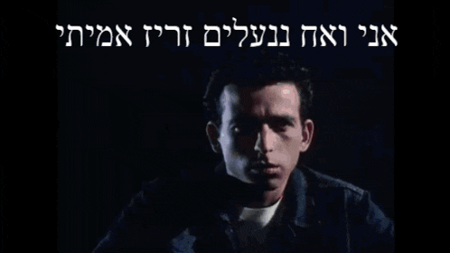 a man riding a motorcycle in the dark with hebrew writing on the bottom right