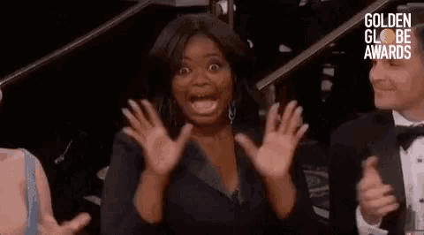 a woman is making a surprised face while sitting in front of a crowd at a awards show .