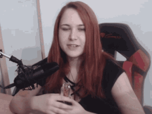 a woman with red hair is sitting in front of a microphone and a gaming chair