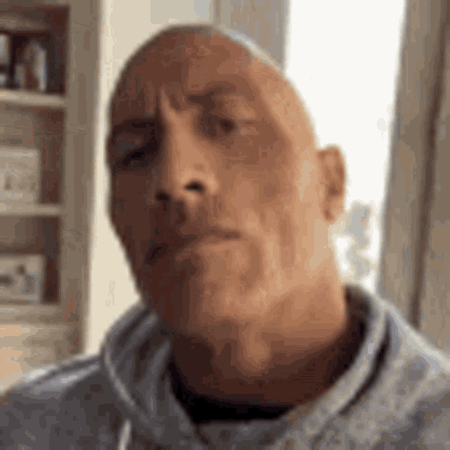 a close up of a bald man wearing a grey hoodie .