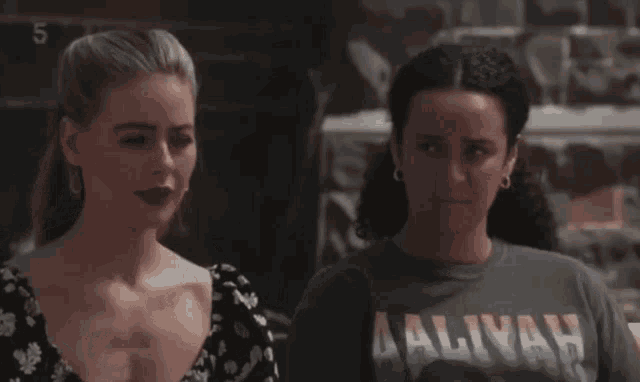 two women standing next to each other with one wearing a t-shirt that says ' aaliyah '