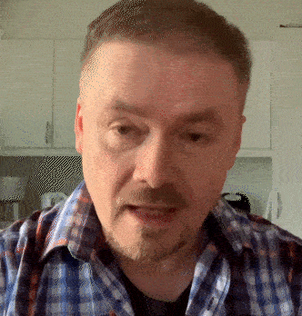 a man with a beard and a plaid shirt looks at the camera