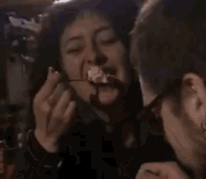 a woman is eating a piece of food with a fork while a man watches .