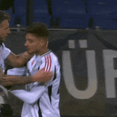 two soccer players are hugging in front of a sign that says s