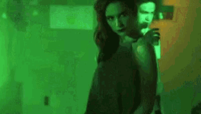a woman is standing in front of a man in a green room .