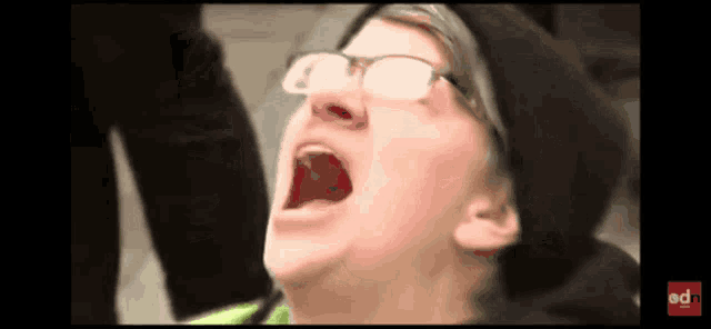 a man wearing glasses and a black hat is screaming