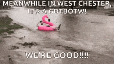 a man is floating on a pink flamingo float in a flooded area .