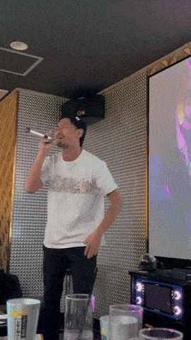 a man singing into a microphone while wearing a shirt that says ' tokyo '