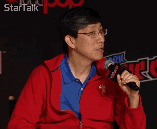 a man in a red jacket is holding a microphone in front of a star talk sign