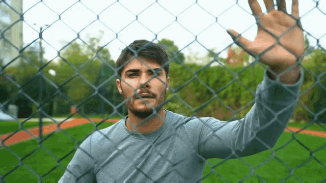 a man is behind a chain link fence with his hand outstretched