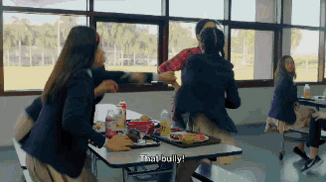 a group of girls are sitting at a table and one girl says that bully