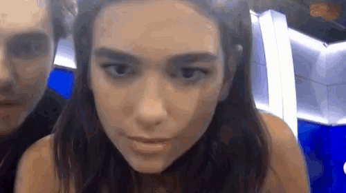 a close up of a woman 's face with a man standing behind her .