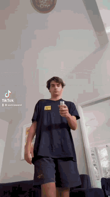a young man is standing in a room holding a cell phone .