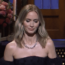 a woman wearing a necklace and a black dress is smiling