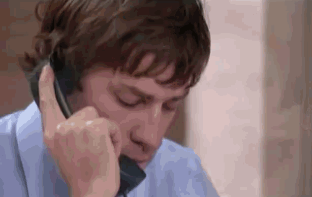 a man in a blue shirt is talking on a phone .