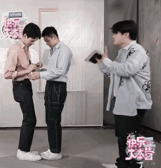 three men are standing in front of a sign that says vivo on it