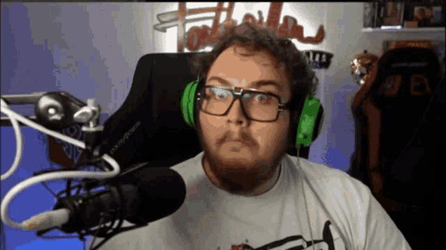 a man wearing glasses and green headphones looks at the camera