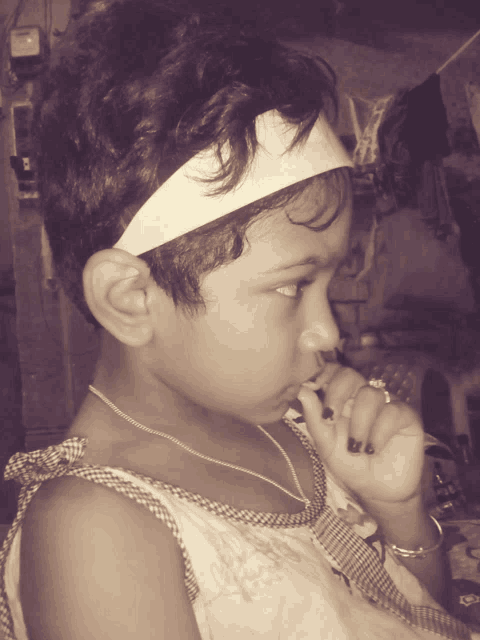 a little girl with a headband on her head looks down