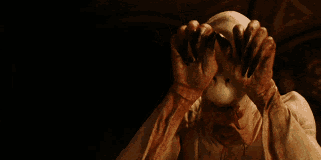 a person with bloody hands is looking at the camera in a dark room