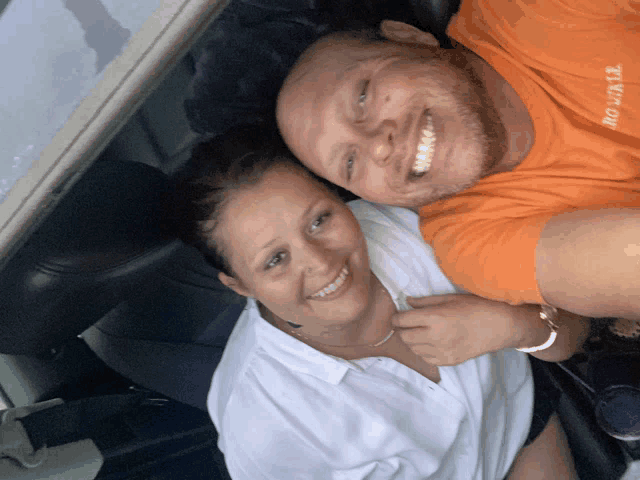 a man and a woman are posing for a picture and the man is wearing an orange shirt that says ' no limits '