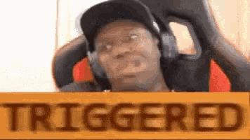 a man wearing headphones is sitting in a chair with a sign that says triggered .