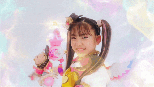 a young girl with pigtails is holding a pink toy