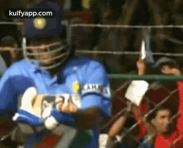 a man wearing a helmet and gloves is standing in front of a crowd .