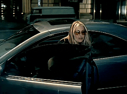 a woman wearing sunglasses is standing in front of a car