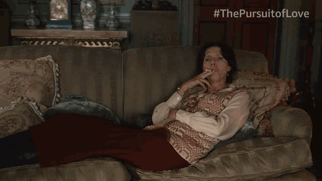 a woman is laying on a couch with a cigarette in her hand and #thepursuitoflove written on the bottom