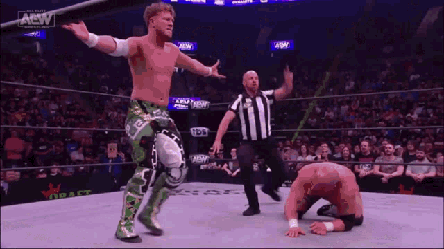 two wrestlers are standing in a ring with a referee .